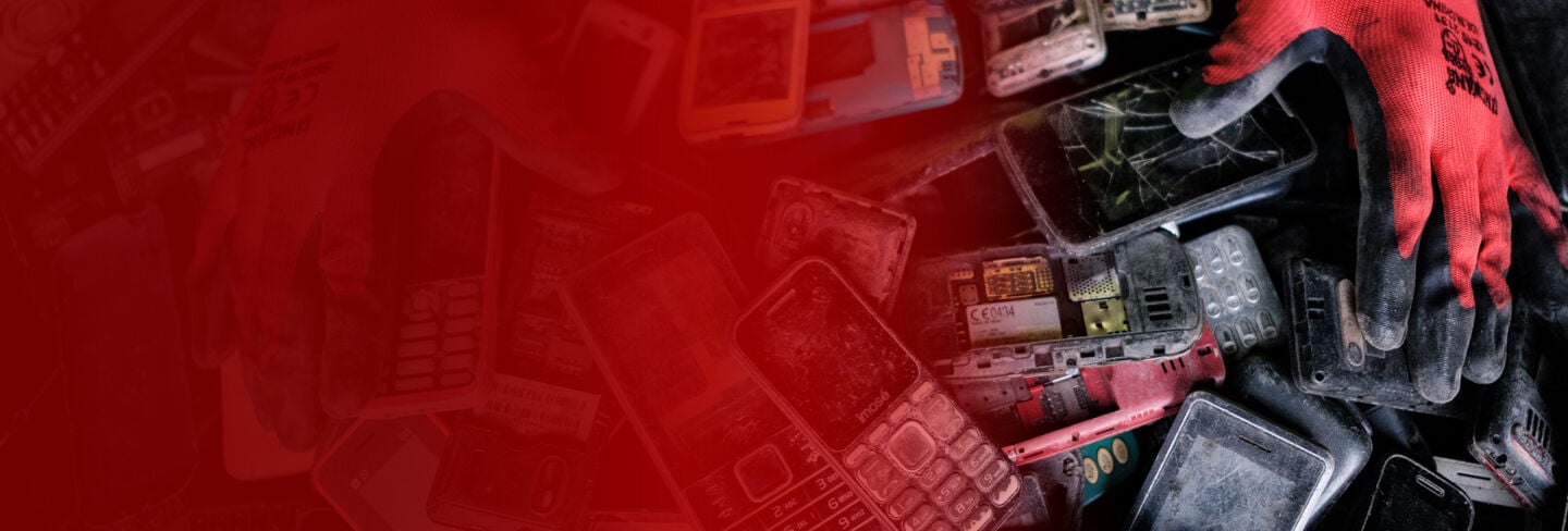Iemand met werkhandschoenen die afgedankte en kapotte telefoons sorteert Iemand met werkhandschoenen die afgedankte en kapotte telefoons sorteert
